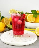 red strawberry lemonade in a glass on a round white wooden board photo