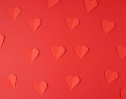 hearts cut out of red paper on a red background, festive backdrop for Valentine's Day photo