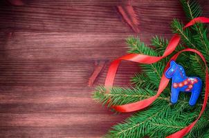 Brown wood background with spruce branch decorated with red ribbon photo