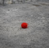 red woolen ball lies on the gray asphalt photo