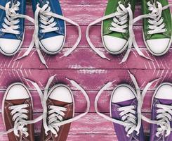 Youth colored sneakers on old pink wooden surface, top view photo