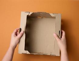 female hands are holding an empty open box of brown cardboard, top view, concept of packing things photo