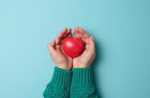 las manos femeninas tienen corazón rojo, fondo azul. concepto de amor y donación, espacio de copia, vista superior foto
