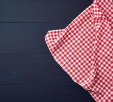 toalla de cocina a cuadros rojos blancos sobre un fondo de madera azul foto