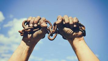 two dirty male hands wrapped in a rusty iron chain photo