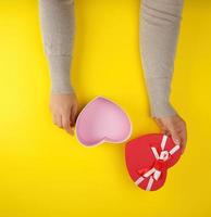 two female hands holding an open red heart-shaped box, festive backdrop photo