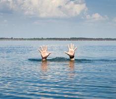 pair of masculine hands sticks out of the sea water on a summer day photo