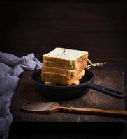 slices of bread made of wheat flour in a round black cast-iron frying pan photo