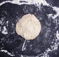 ball of wheat yeast dough on a black surface photo