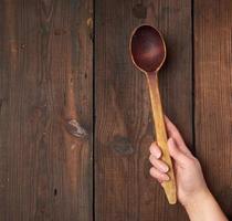 hand holds an old brown wooden spoon photo
