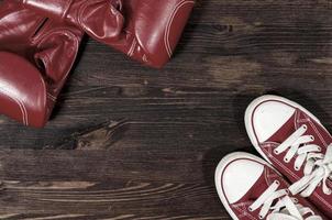 Red boxing gloves and red sneakers on a wooden surface photo