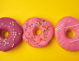 round different sweet donuts with sprinkles on a yellow background photo