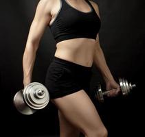 young woman of Caucasian appearance holds steel type-setting dumbbells in her hands photo