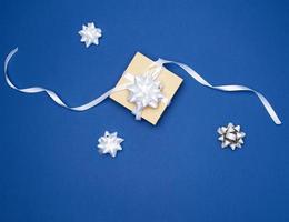 square box with a gift tied with a white ribbon with a bow on a blue background photo