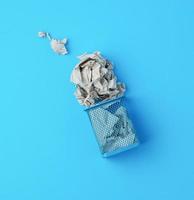 overturned blue metal basket with crumpled pieces of paper photo