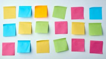 three rows of blank square paper multicolored stickers on a white wall photo