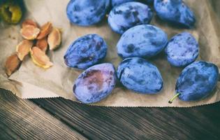 ripe blue plums on brown paper, photo