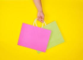 hand holding two paper shopping bags on a yellow background photo