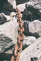 old rusty chain lies in the middle of the stones photo