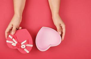 two hands hold a paper open red box in the shape of a heart photo