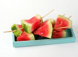 sliced ripe red watermelon with seeds on a wooden blue board photo