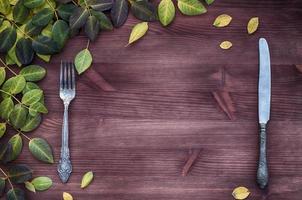 Knife and fork on a brown wooden surface, empty space photo