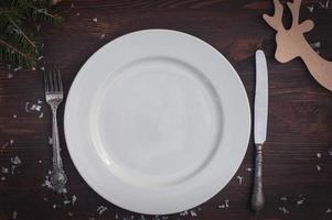 White plate with silver knife and fork on brown wooden surface Christmas table setting photo