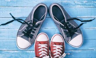 Two pairs of textile sneakers with loose laces stand opposite each other photo