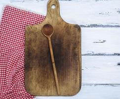 tabla de cortar de cocina vieja marrón y cuchara de madera foto