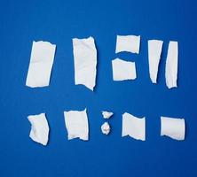 set of various pieces of torn white crumpled paper on a blue background photo