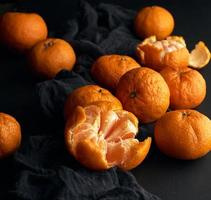 mandarina naranja madura pelada y un montón de frutas enteras redondas sin pelar foto