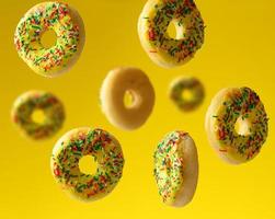 round baked donuts sprinkled with multicolored sugar sprinkle levitate on a yellow background photo