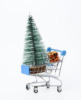 Compras meiallic con regalo y árbol de navidad en miniatura aislado sobre fondo blanco. foto