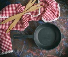 round empty black cast-iron frying pan with a red napkin photo