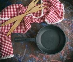 round empty black cast-iron frying pan with a red napkin photo