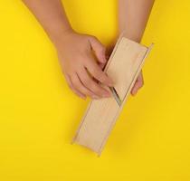 rallador de madera para verduras en las manos sobre un fondo amarillo foto