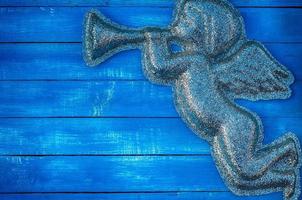 Figure angel of shiny particles on a blue wooden background photo