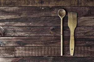 espátula de cocina de madera y una cuchara sobre una superficie marrón foto