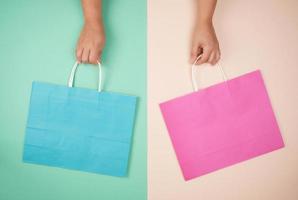 two hands holding paper shopping bags on abstract color background photo