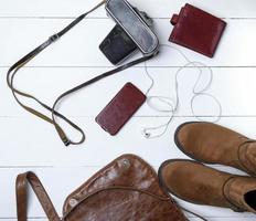 leather brown boots, smartphone in a case with headphones, purse and old vintage camera in a black case photo