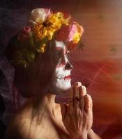 la chica con el pelo negro está vestida con una corona de rosas multicolores y el maquillaje está hecho en su cara de calavera de azúcar foto