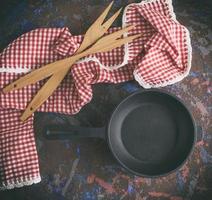 black cast-iron frying pan with a handle and two wooden forks photo