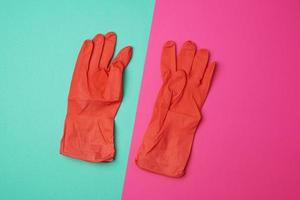 un par de guantes naranjas de goma para limpiar la casa con un fondo de color foto
