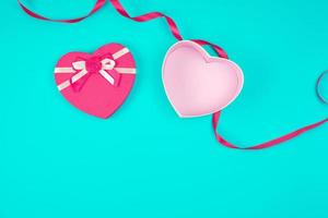 open pink heart-shaped gift box with a bow on a blue background photo