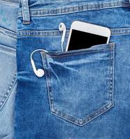 smartphone blanco con auriculares en el bolsillo trasero de blue jeans foto