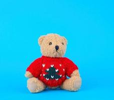 traditional toy teddy bear dressed in a red knitted sweater sits photo