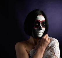 mujer con cabello corto negro en cabeza de azúcar de maquillaje blanco para el día de los muertos foto