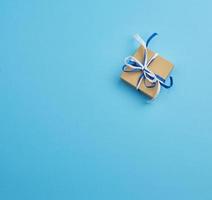 brown cardboard gift square box, bows on a blue background photo