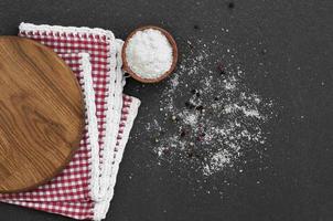 White salt in a wooden bowl on a black surface photo