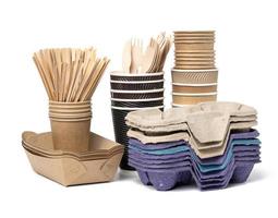 stack of brown disposable paper cups, wooden forks and knives, plate on a white background. Utensils for takeaway drinks photo
